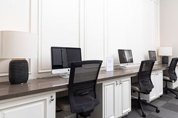 A row of computers sitting on top of a wooden desk